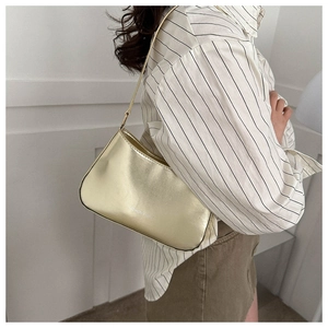 Fashionable gold metallic underarm bag with Fashion & Home print on model