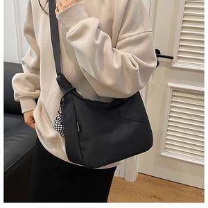 Détail du sac croissant en nylon noir avec étiquette mode et pendentif damier