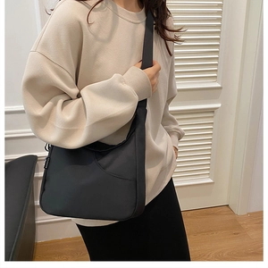 Détail d'un sac bandoulière en nylon noir avec sangle réglable et étiquette mode