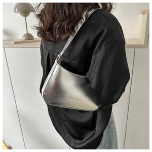 Close-up of metallic silver underarm bag with glossy finish and thin shoulder strap