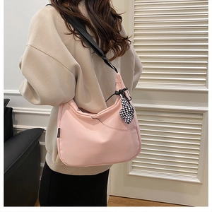 Détail du sac fourre-tout rose en croissant avec bandoulière noire et breloque en damier