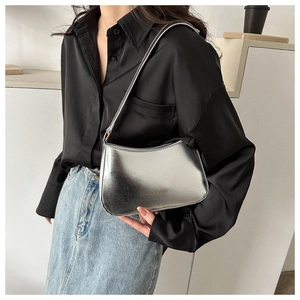 Silver metallic crescent underarm bag styled with black satin shirt and blue denim skirt