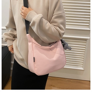 Détail du sac croissant rose clair avec sangle noire et pendentif damier