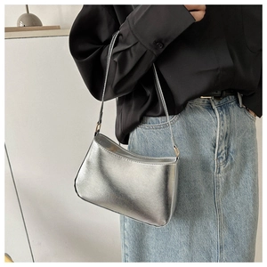 Close-up of a silver metallic shoulder bag with golden buckles on a black shirt background