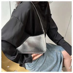 Close-up of silver metallic shoulder bag showing glossy PU texture and shoulder strap
