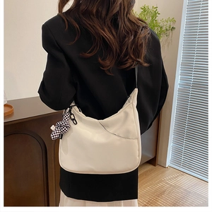 Détail du sac bandoulière blanc en demi-lune avec un porte-clés lapin à damier noir