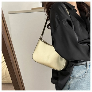 Detail of champagne gold underarm bag in glossy finish with sleek metallic luster
