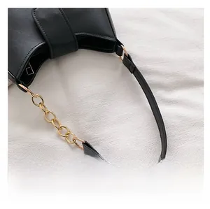 Gros plan détaillé d'un sac besace noir en cuir avec chaîne en métal doré et bandoulière