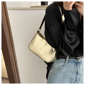 Detail of a metallic gold underarm bag with sleek surface and durable metal hardware