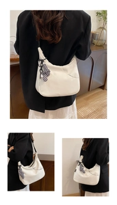 Détail du sac cabas blanc avec breloque nœud à damier noir et blanc pour usage quotidien