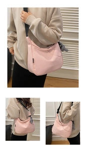 Détail du sac demi-lune rose avec large bandoulière noire et charm nœud en damier