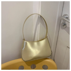 Close-up of champagne gold glossy shoulder bag with Fashion Bags text on a chair