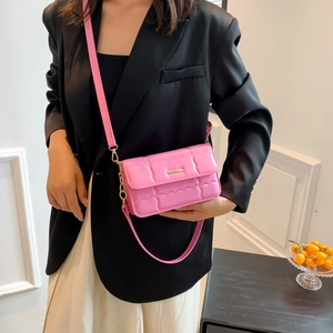 Roze gewatteerde crossbodytas met gouden ketting getoond op een model in kleding