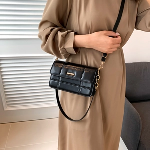 Klassieke zwarte gewatteerde crossbodytas met gouden hardware bij een beige jurk