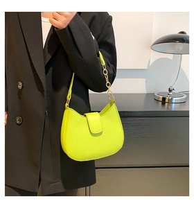 Détail d'un sac à main vert néon avec bandoulière chaîne dorée et fermoir en métal