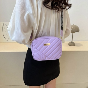 Lavender quilted camera bag with stylish wide letter strap shown on a model