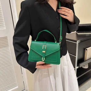 Green croc-embossed small square handbag with golden buckle shown on a model's shoulder