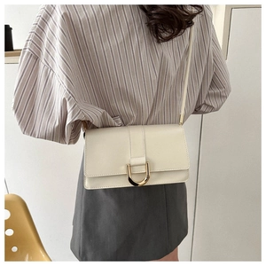 Close-up of ivory PU leather crossbody bag with gold D-ring buckle on female model