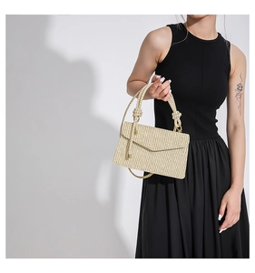 Detail of beige woven handbag with knot handle and gold hardware on a model