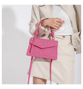 Detailed view of pink woven handbag with knotted handle and gold metal hardware on model
