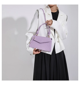 Close-up of a purple woven texture crossbody bag with a knot handle and elegant flap design