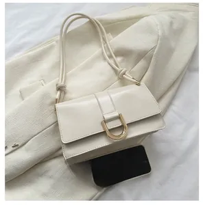 Close-up of cream rectangular baguette bag with gold horse-shoe metal buckle and leather strap