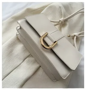 Detail of a creamy white leather shoulder bag featuring a gold D-shaped buckle and gusseted side