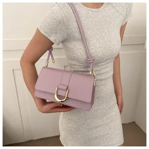 Detail of a purple leather crossbody bag with a golden horseshoe buckle and knotted strap