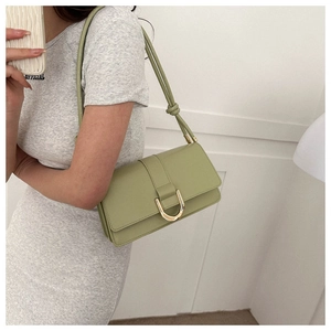 Detail of light green shoulder bag with golden horseshoe clasp and knotted strap detail