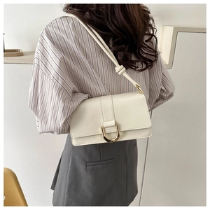 Detail of cream leather shoulder bag with gold metal hardware on model in striped shirt