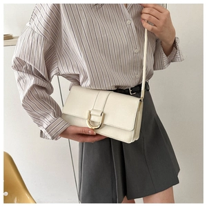 Detail of cream white leather crossbody bag featuring a gold D-ring buckle and slim strap
