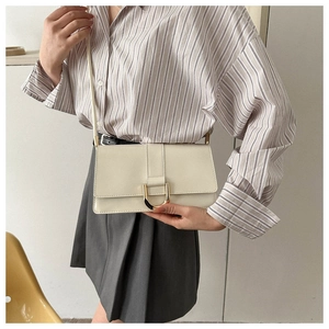 Detail of off-white crossbody bag with gold U-shaped buckle on striped shirt outfit