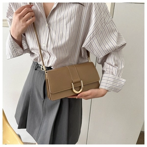 Detail of khaki leather crossbody bag featuring a golden horseshoe buckle on the flap