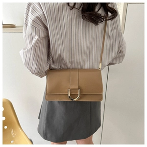 Brown retro shoulder bag with gold horseshoe buckle worn with a striped shirt