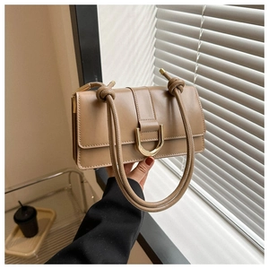 Detail of tan PU leather crossbody bag with gold D-ring buckle and knotted handle design