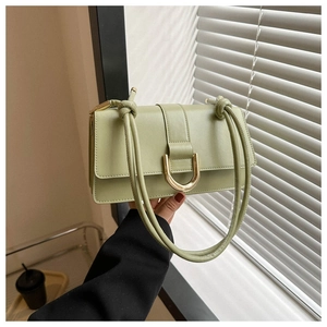 Detail of mint green PU leather bag featuring a gold horseshoe buckle and knotted strap