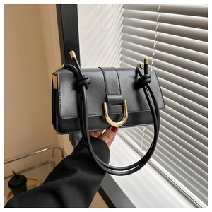 Detail view of a black PU leather bag with golden U-shaped buckle and knotted shoulder strap