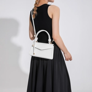 White woven texture crossbody handbag with gold hardware shown on a female model