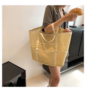 Detalle de bolso tote grande de malla amarilla con correas reforzadas para la compra