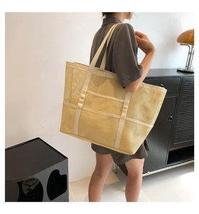 Detalle de un gran bolso tote de malla amarilla con asas reforzadas en color crema con modelo