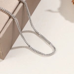 Collier chaîne épi en acier inoxydable argenté exposé sur une boîte à bijoux