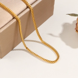 Élégant collier chaîne Franco plaqué or drapé sur un coffret à bijoux texturé raffiné