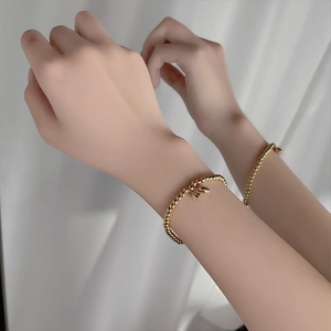 Minimalist gold beaded bracelet with lotus seed charms on a soft white background
