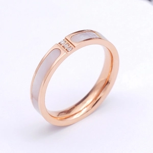 Close-up of rose gold ring with white shell inlay and three small diamonds detail