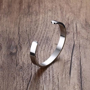 Minimalist C-shaped polished titanium steel open cuff bracelet on dark wood background