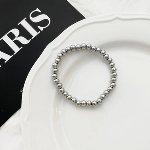 Minimalistische zilveren roestvrijstalen kralenarmband op een wit keramisch bord