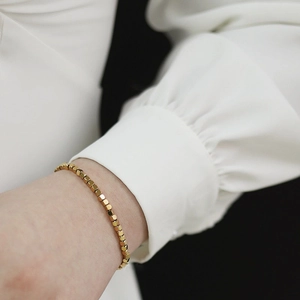 Elegant gold titanium steel bracelet featuring minimalist faceted cube metal beads