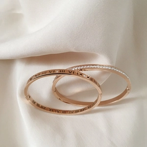 Detail of rose gold Roman numeral bangles with sparkling crystals on silk fabric