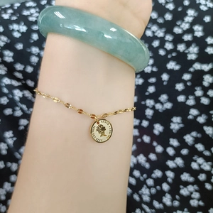 Gold queen coin pendant bracelet and green jade bangle set on floral dress sleeve