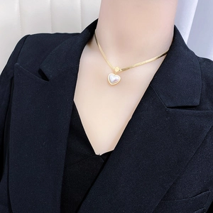 Gold snake chain necklace with heart pendant and white shell inlay on black suit